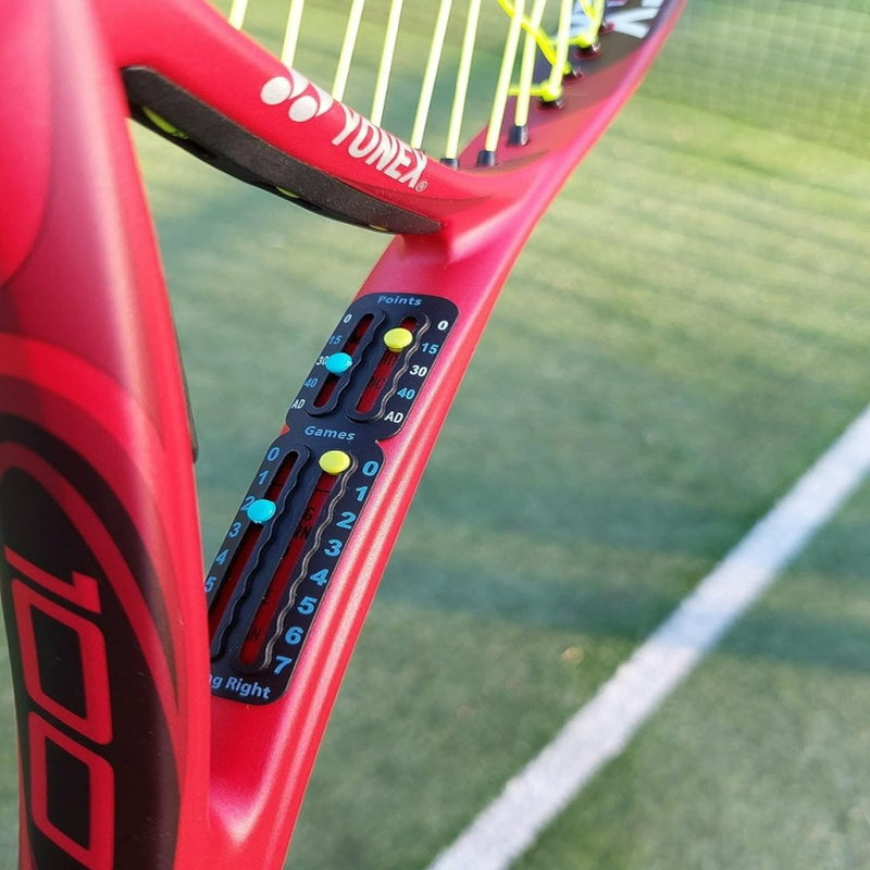 Load image into Gallery viewer, Een close-up van een rood racket toont het Draagbaar tennis scorebord, waarop de punten en games op een groene baan worden bijgehouden.
