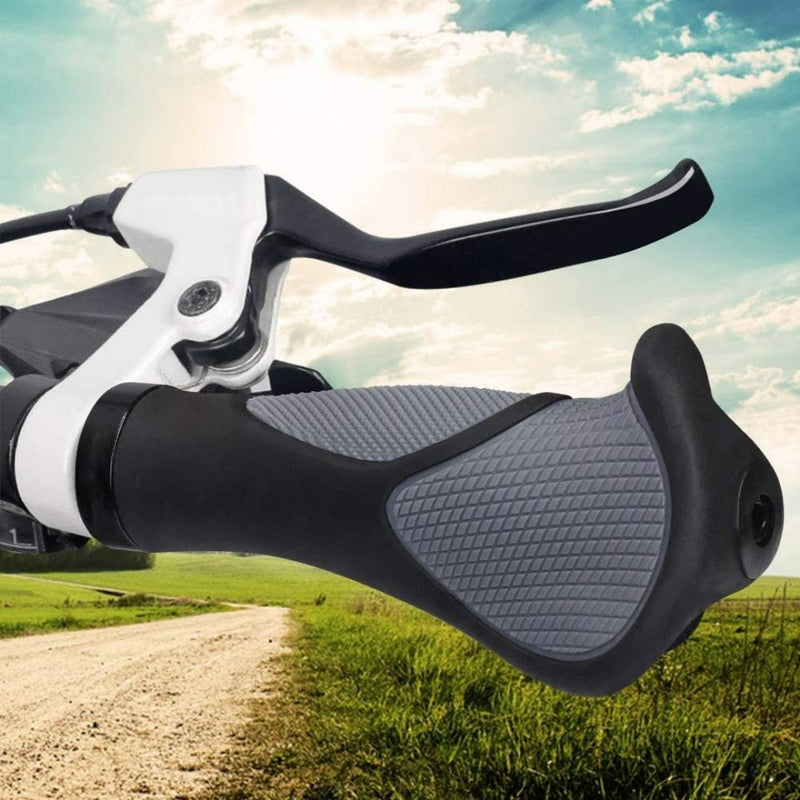 Load image into Gallery viewer, Close-up van een Mtb-handvat met antislip rubberen handvat en remhendel, tegen de achtergrond van een landelijk onverhard pad en groene velden onder een gedeeltelijk bewolkte hemel.
