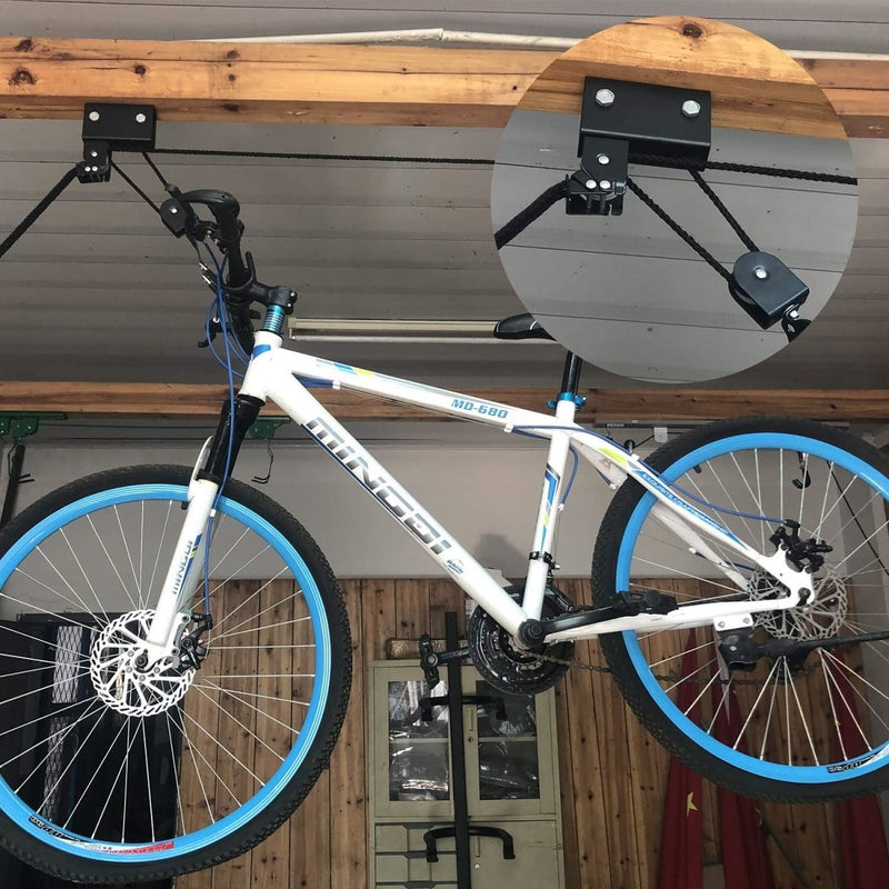 Load image into Gallery viewer, Een witte mountainbike met blauwe velgen hangt aan het plafond van een garage met ons product &quot;Optimaal ruimtegebruik en veiligheid: Ontdek onze fietslift!&quot; presentatie van het fietstakelmechanisme en ruimtebesparing.
