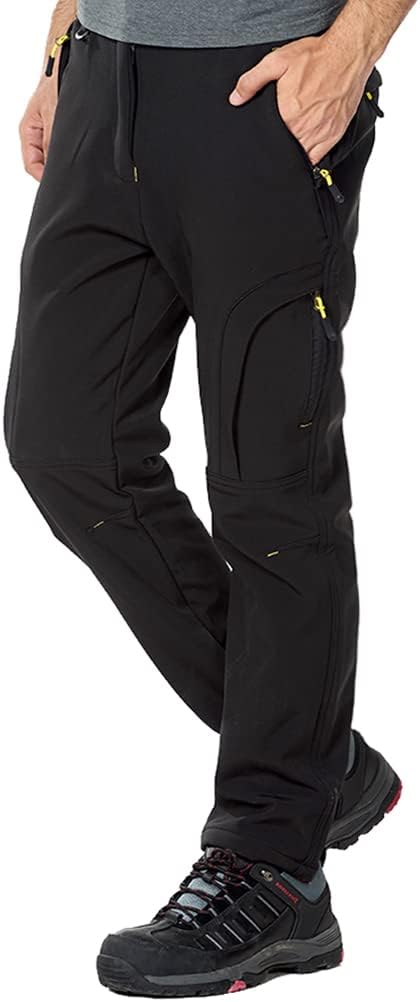 Een persoon die een zwarte cargobroek en zwarte wandelschoenen draagt, staat in de wandel- en skibroek: houd je warm en comfortabel in de koude, waterafstotend voor onvoorspelbaar weer.