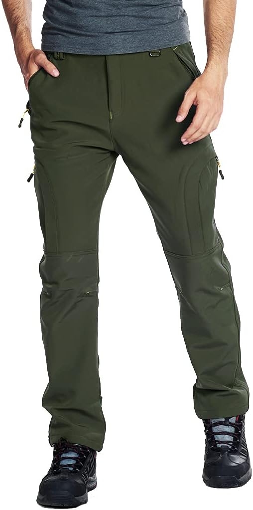 Laad afbeelding in Galerijviewer, Een persoon die de groene Houd je warm en comfortabel in de koude met de heren wandel en skibroek en een grijs shirt draagt, staat met de handen in de zakken, terwijl in de buurt zwarte wandelschoenen zichtbaar zijn.
