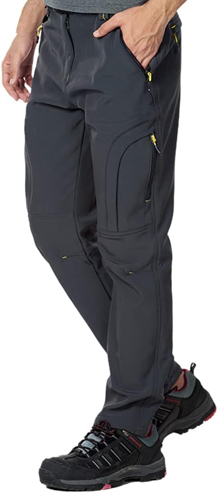 Een persoon gekleed in de Houd je warm en comfortabel wandel en skibroek, donkergrijs met ritsen, gecombineerd met zwarte wandelschoenen met rode accenten, is klaar voor elk avontuur.