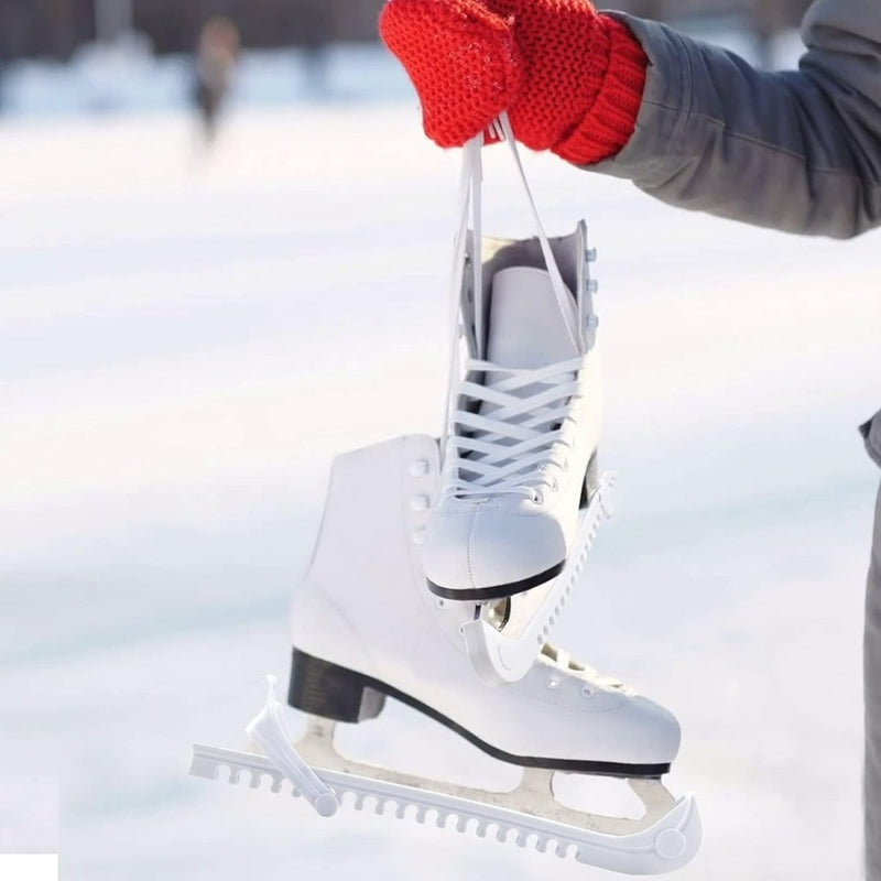 Laad afbeelding in Galerijviewer, Rood gehandschoende handen houden witte kunstschaatsen vast met Schaatsbeschermers: houd je schaatsen in topconditie op de schaatsen en biedt slijtagebescherming tegen een besneeuwde achtergrond.
