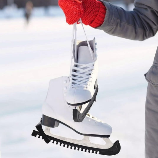 Een persoon met rode handschoenen houdt witte schaatsen bij de veters vast tegen een besneeuwde achtergrond. De schaatsen zijn voorzien van "Schaatsbeschermers: houd je schaatsen in topconditie" voor verbeterde slijtagebescherming, waardoor duurzaamheid op ijzig terrein wordt gegarandeerd.