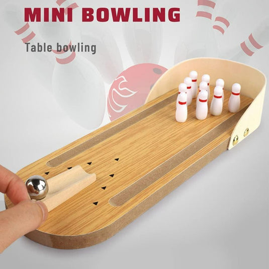 Een hand staat klaar om een metalen bal te rollen op de "Breng de spanning van de bowlingbaan naar je eigen tafel", een mini houten bowlingset die met tien kleine pinnetjes een authentieke ervaring biedt en tevens dienst doet als stijlvol tafeldecor.