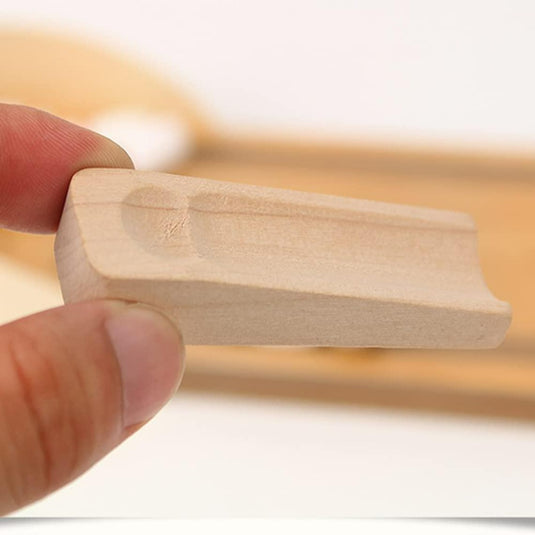 Een persoon houdt een kleine, ongeverfde houten deurstopper met groeven tussen duim en vinger vast tegen een onscherpe achtergrond, die doet denken aan de stukken uit "Breng de spanning van de bowlingbaan naar je eigen tafel met onze mini houten bowlingset!.