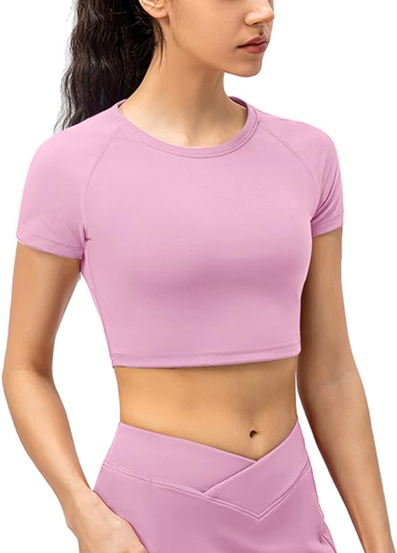 Laad afbeelding in Galerijviewer, Een persoon draagt een roze korte mouwen Naadloze dames fitness crop top, gecombineerd met een high-waisted legging gemaakt van versleten stof. Deze crop top biedt 4-way stretch voor ultiem comfort en maximale bewegingsvrijheid tijdens elke activiteit.
