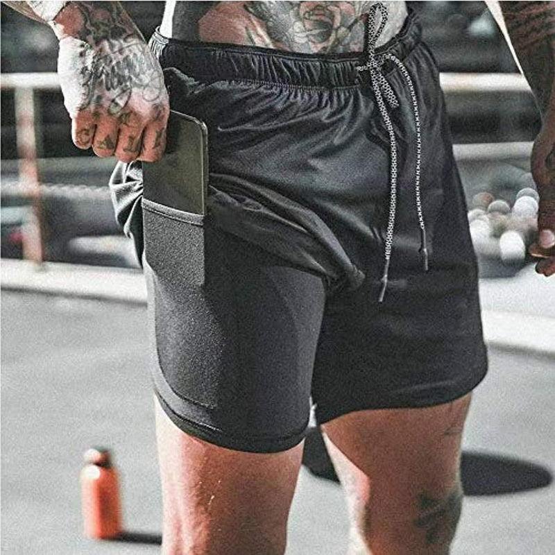 Laad afbeelding in Galerijviewer, In de sportschool draagt iemand de &quot;Ontdek het ultieme comfort en functionaliteit van onze heren 2-in-1 shorts&quot;, gemaakt van sneldrogend materiaal. De comfortabele zwarte atletiekshort heeft een zijzak waarin je een smartphone kunt opbergen terwijl je naast een waterfles staat.
