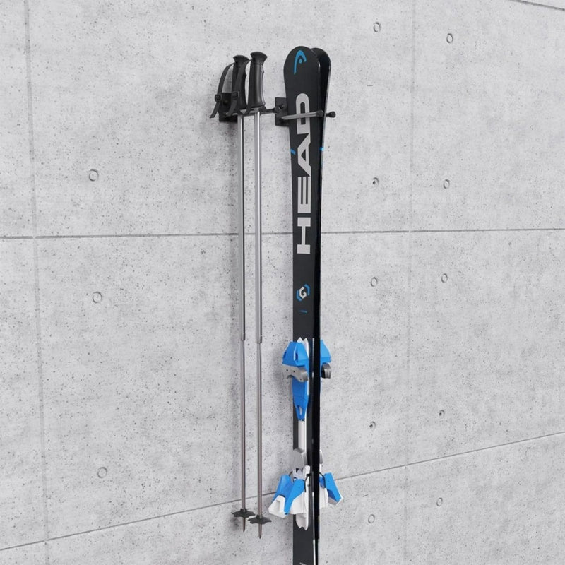 Laad afbeelding in Galerijviewer, Een paar blauw-zwarte ski&#39;s met met rubber beklede stokken zijn elegant gemonteerd op een grijze betonnen muur met behulp van de &quot;Ski-opslag op de muur: een praktische en duurzame oplossing voor je ski&#39;s.
