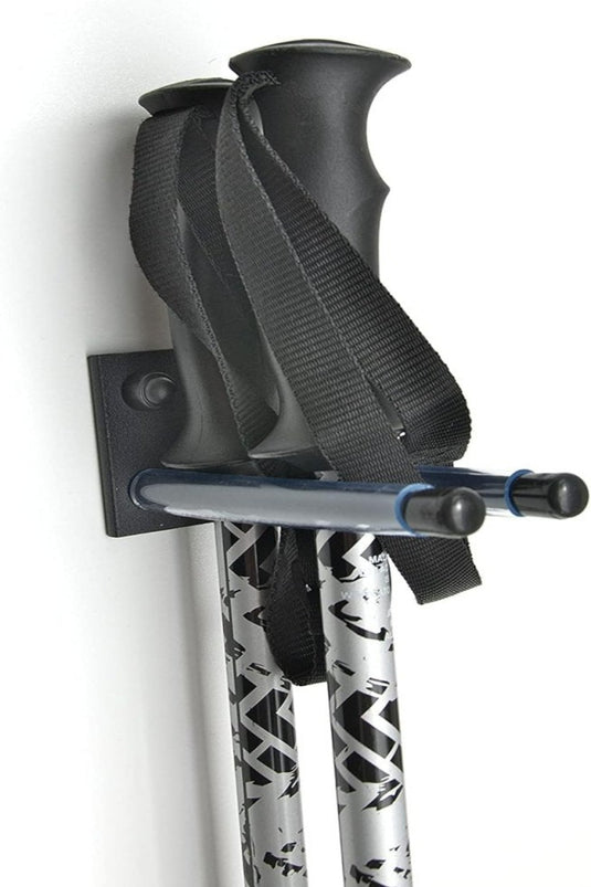 Op de "Ski-opslag op de muur: een praktische en duurzame oplossing voor je ski's" zijn twee trekkingstokken met zwarte handvatten en polsbanden, voorzien van een strak zilver en zwart design, gemonteerd.