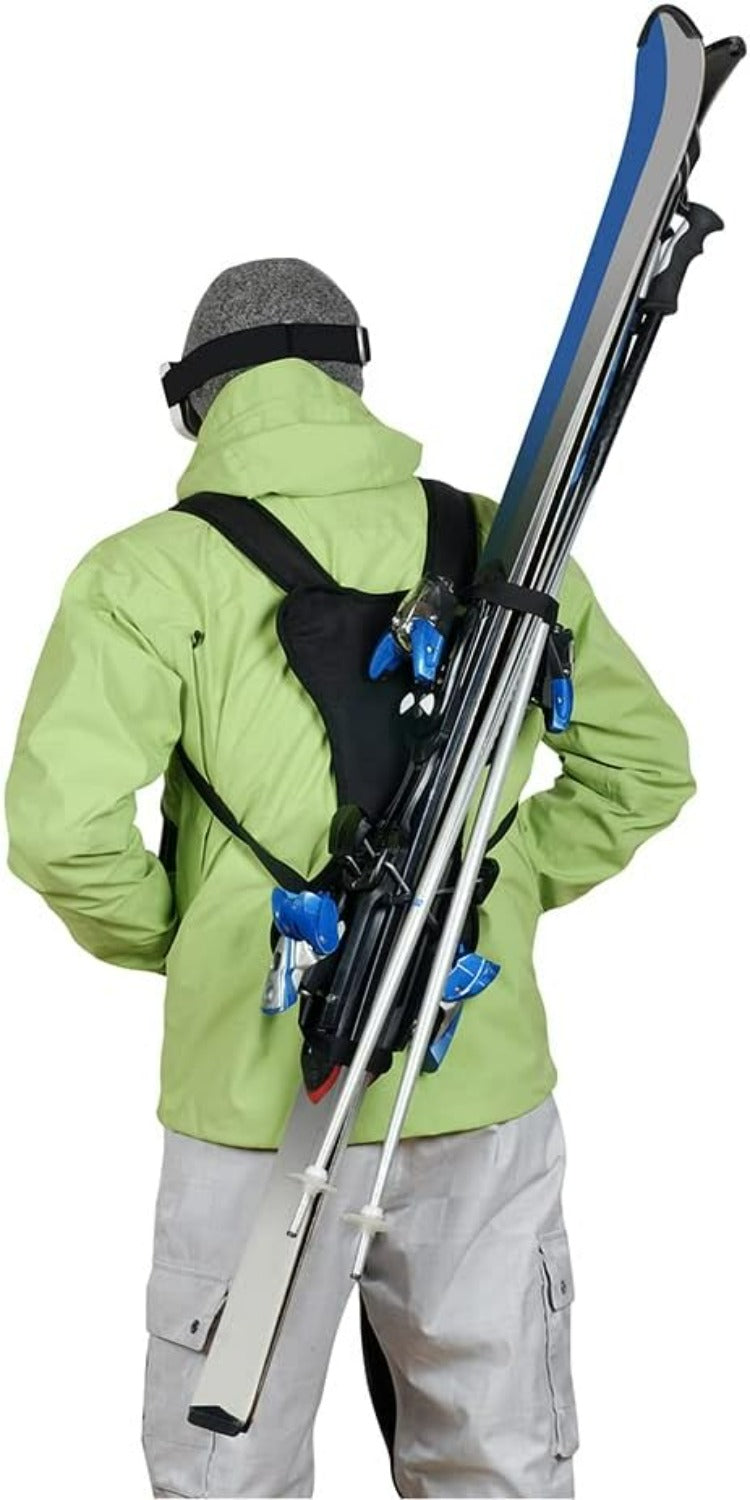 Load image into Gallery viewer, Een persoon in een groene jas draagt moeiteloos ski&#39;s en stokken op de rug met het zwarte &quot;Skiën zonder je handen te gebruiken? Met de skiback is het mogelijk!&quot;, waarmee hij de handenvrij ski-ervaring omarmt. Dit accessoire is comfortabel en compact, perfect voor avontuurlijke hellingen.
