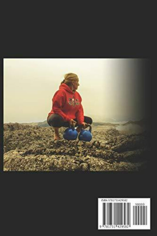 Iemand draagt een rode hoodie, hurkt op rotsen en voert een kettlebell snatch uit met twee blauwe kettlebells onder een bewolkte lucht. Dit illustreert de intensiteit die wordt beschreven in 'Snatch Physics: Leer kettlebell snatchen in 21 dagen'.