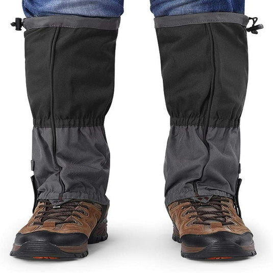 Iemand draagt bruine wandelschoenen met de tekst "Ontdek het ultieme comfort en bescherming met onze sneeuw gamaschen voor volwassenen" over een spijkerbroek, wat zorgt voor beenbescherming en comfort.