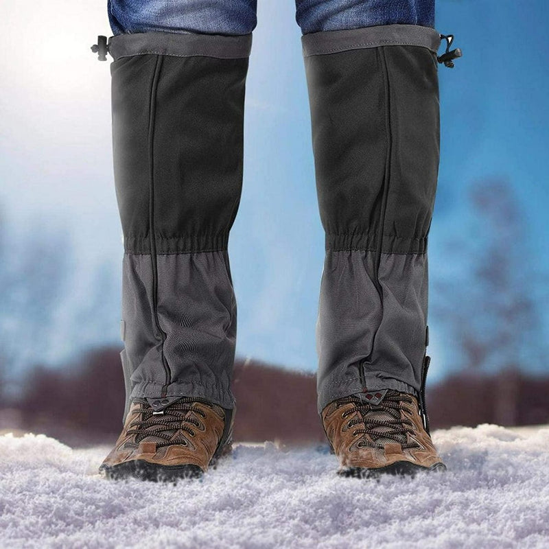 Laad afbeelding in Galerijviewer, Een persoon in bruine wandelschoenen en onze volwassen sneeuwgamaschen staan op de sneeuw, perfect winddicht, met een wazig sneeuwlandschap dat een magische winterse charme toevoegt.
