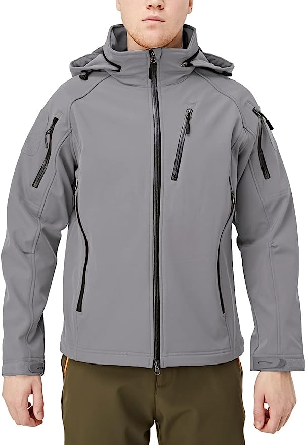 Laad afbeelding in Galerijviewer, Een persoon staat tegen een effen witte achtergrond en draagt de &quot;Blijf warm en droog in elke weersomstandigheid met de waterafstotende softshell jas&quot;, met een grijze capuchon, fleecevoering en meerdere zakken met ritssluiting, gecombineerd met een olijfkleurige broek.

