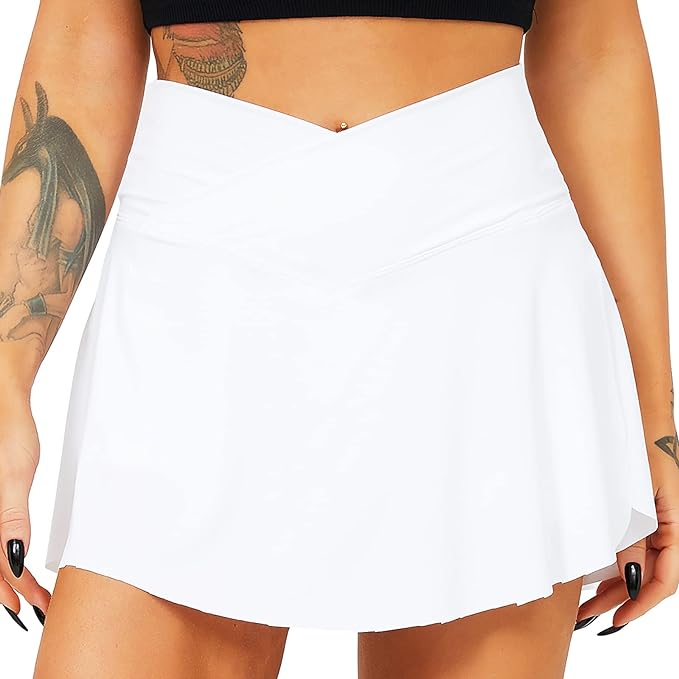 Laad afbeelding in Galerijviewer, Persoon draagt een zwarte crop top en de Tennisrok met broek, de perfecte sportoutfit voor elke vrouw, met zichtbare tatoeages op armen en buik.
