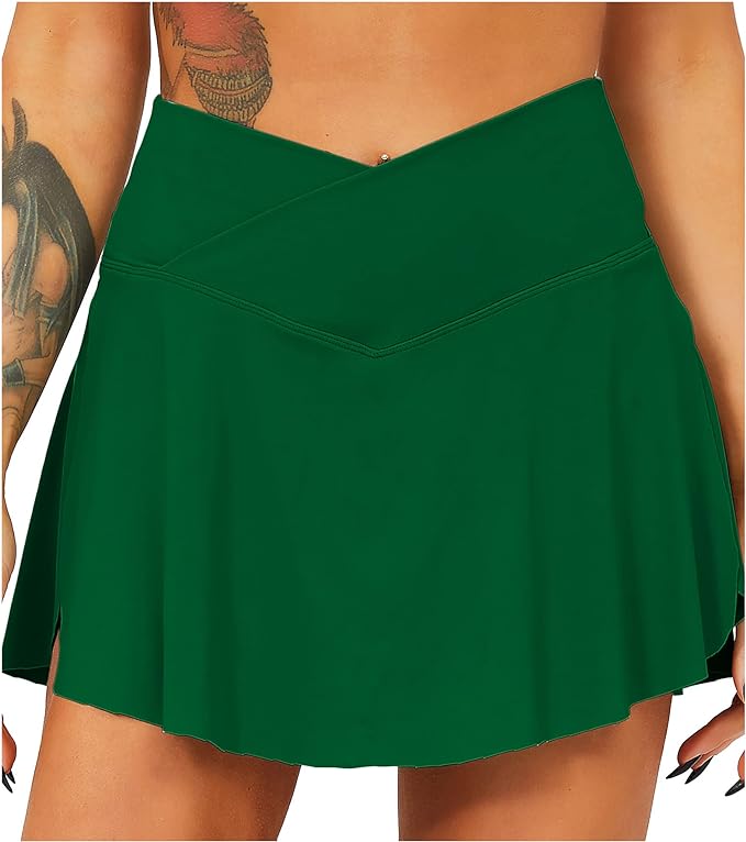 Laad afbeelding in Galerijviewer, Het dragen van een groene asymmetrische rok, die doet denken aan de Tennisrok met broek: de perfecte sportoutfit voor elke vrouw, een persoon met tatoeages op zijn armen combineert stijl en functionaliteit.
