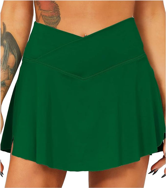 Het dragen van een groene asymmetrische rok, die doet denken aan de Tennisrok met broek: de perfecte sportoutfit voor elke vrouw, een persoon met tatoeages op zijn armen combineert stijl en functionaliteit.