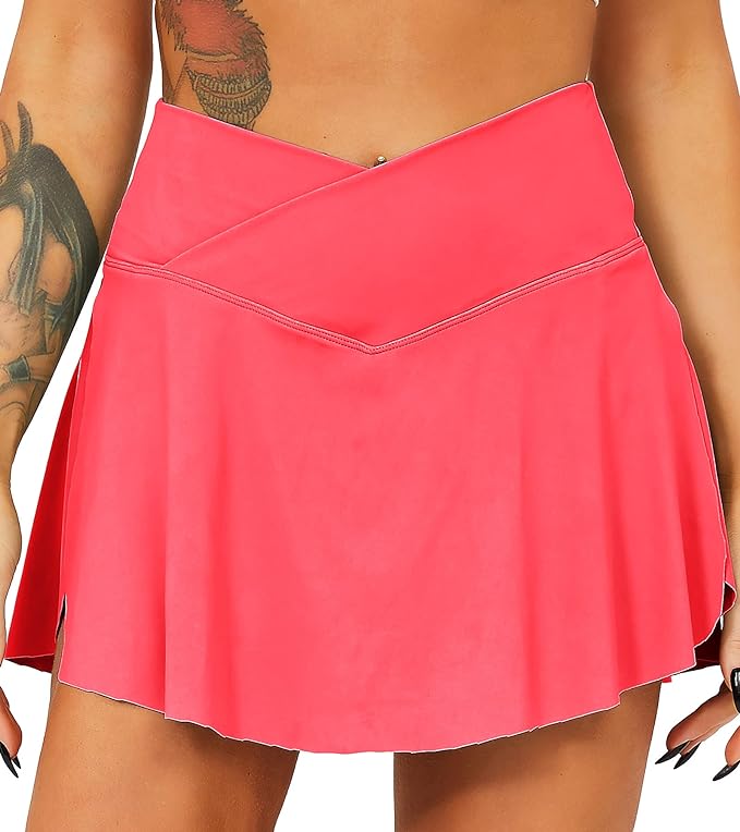 Laad afbeelding in Galerijviewer, Een persoon met tatoeages draagt de Tennisrok met broek, een felroze, hoog getailleerde rok met een V-vormige tailleband, voorzien van praktische zakken.
