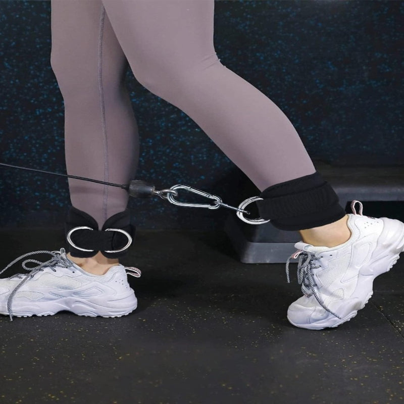 Laad afbeelding in Galerijviewer, De benen van een persoon in grijze leggings en witte sneakers, die de Versterk je been en billen met de foot loop exerciser op een kabelmachine in de sportschool gebruikt voor intensieve been- en bilspiertraining.
