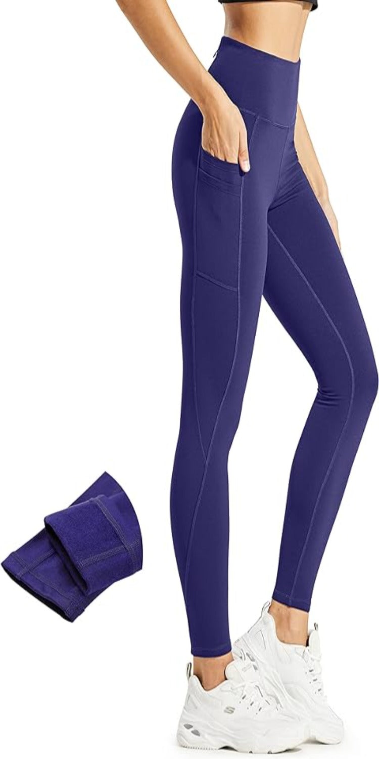 Laad afbeelding in Galerijviewer, Een persoon draagt de perfecte thermische leggings voor vrouwen, hoog getailleerde en paarse met zijzakken, gecombineerd met witte sneakers. Een bijpassende gevouwen stof ligt ernaast.
