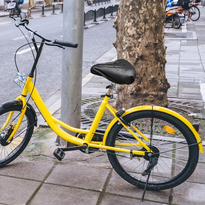 Load image into Gallery viewer, Een gele fiets met de Geniet van comfortabele fietsen met onze hoogwaardige zadelhoezen voor optimale bescherming staat geparkeerd op een nat trottoir naast een boom en paal, waarvan de fietszadel lichtjes glinstert.
